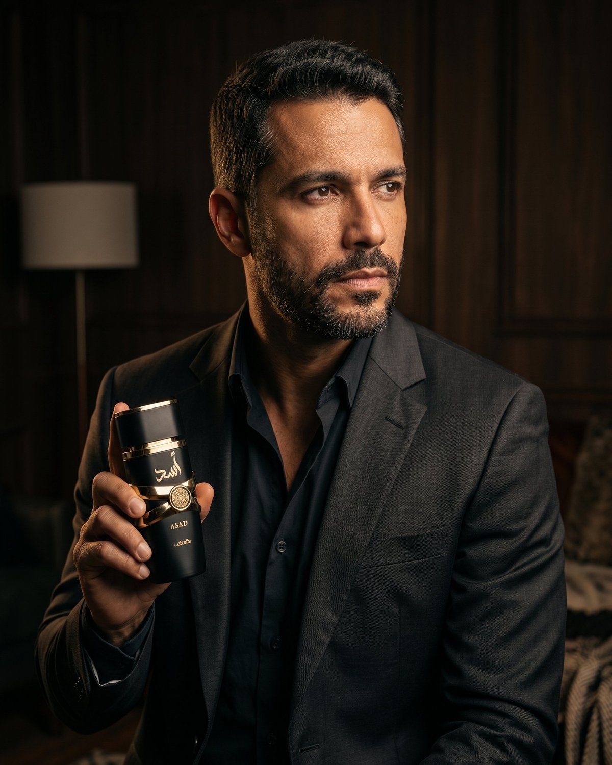 Homem contemplativo segurando Asad Lattafa — ZAYRAH Perfumaria
